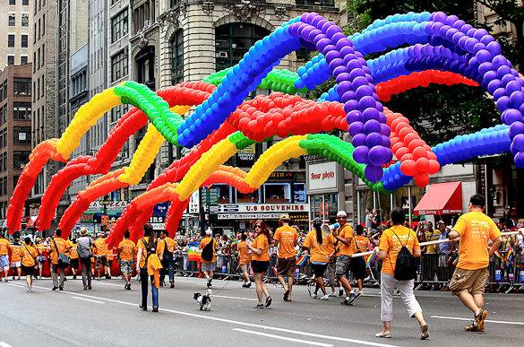 Marchers in NYC Pride parade carrying balloons in rainbow colors