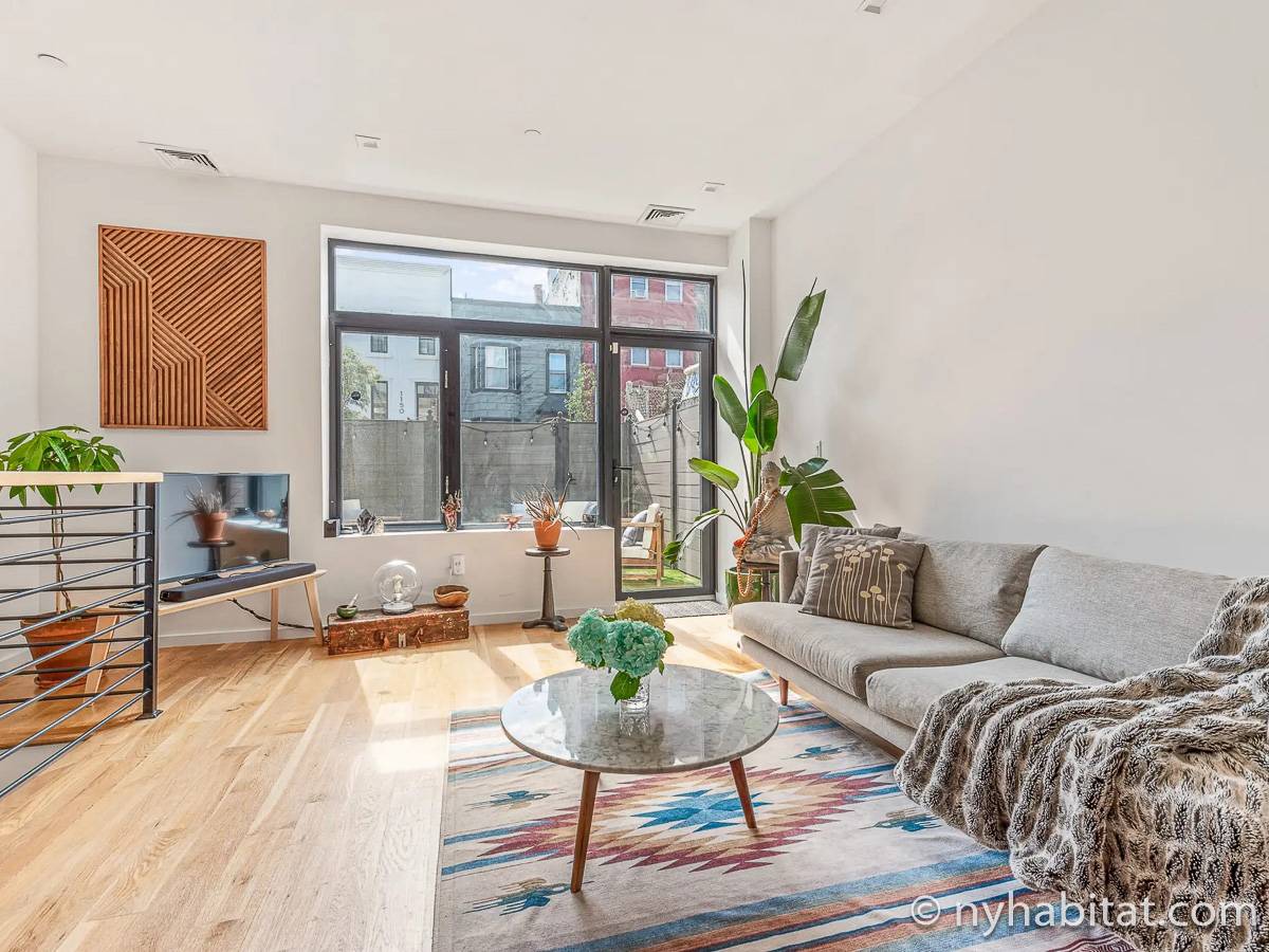 Stylish living room with natural light, modern furnishings, and a comfortable gray sectional sofa in Bushwick (NY-20009)