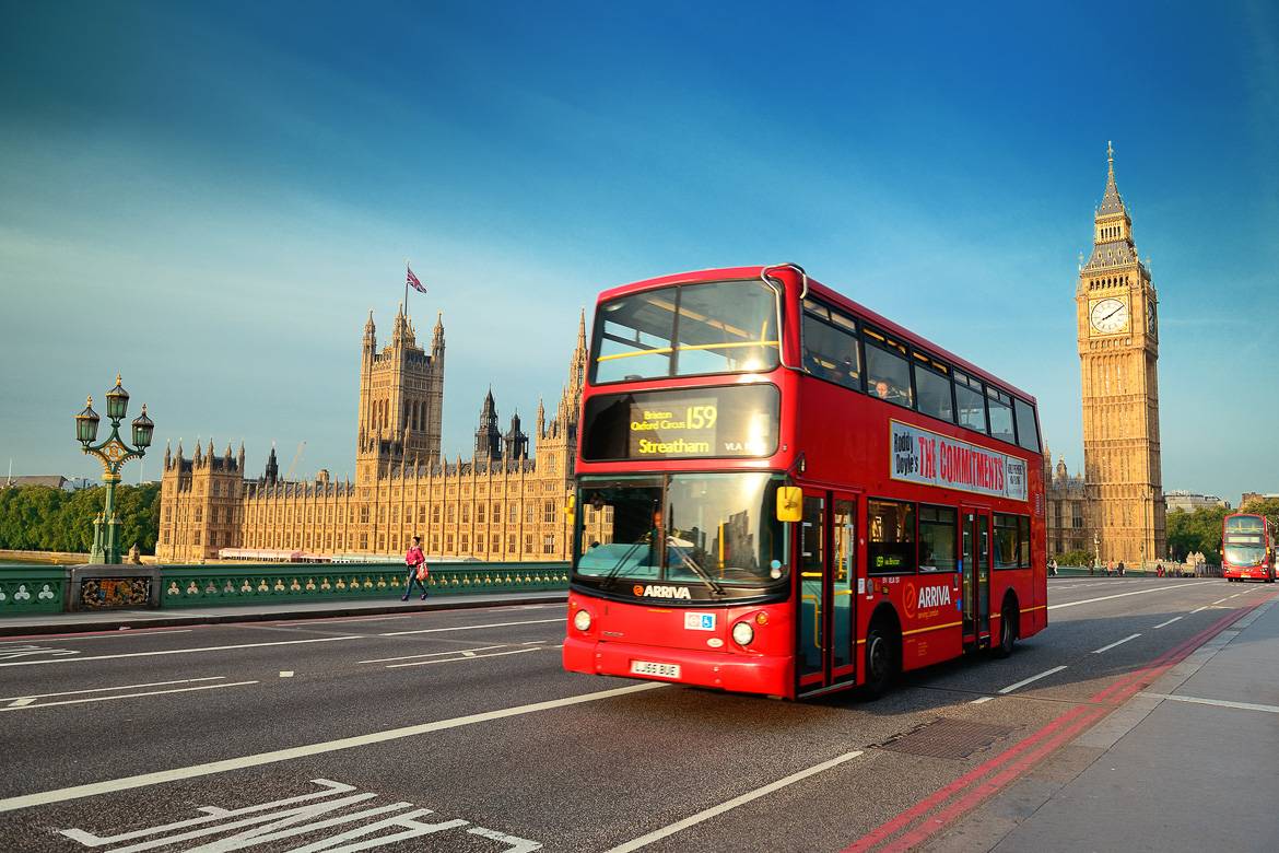Image of a double decker bus on a road in front of the Palace of Westminster, London