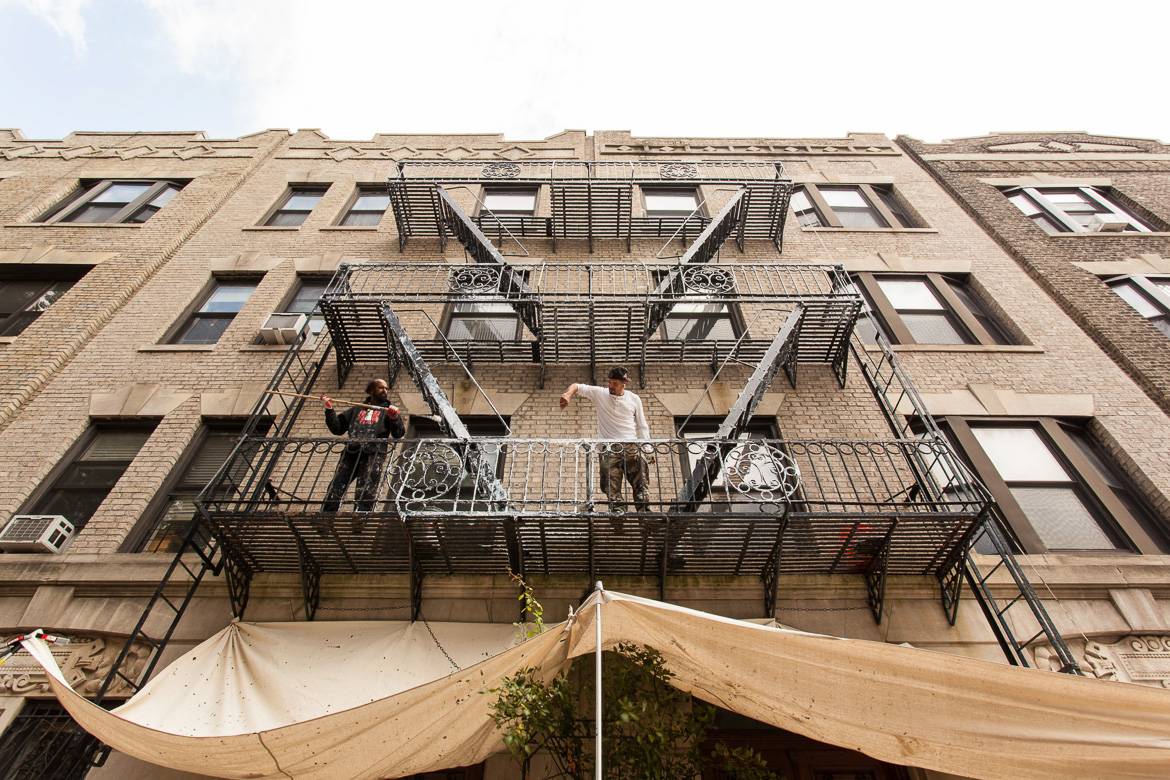 Image of two men on the second story of a fire escape outside a grey building