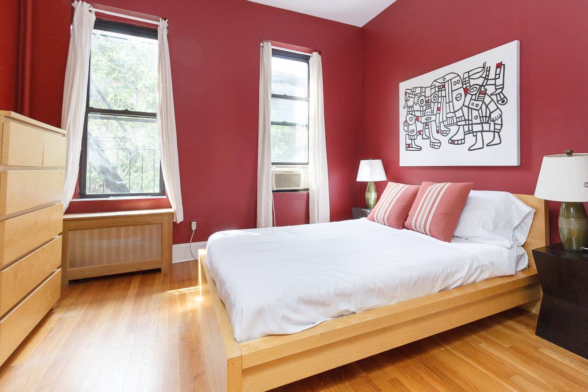 Image of a bedroom in a furnished rental with an air conditioner and fire escape
