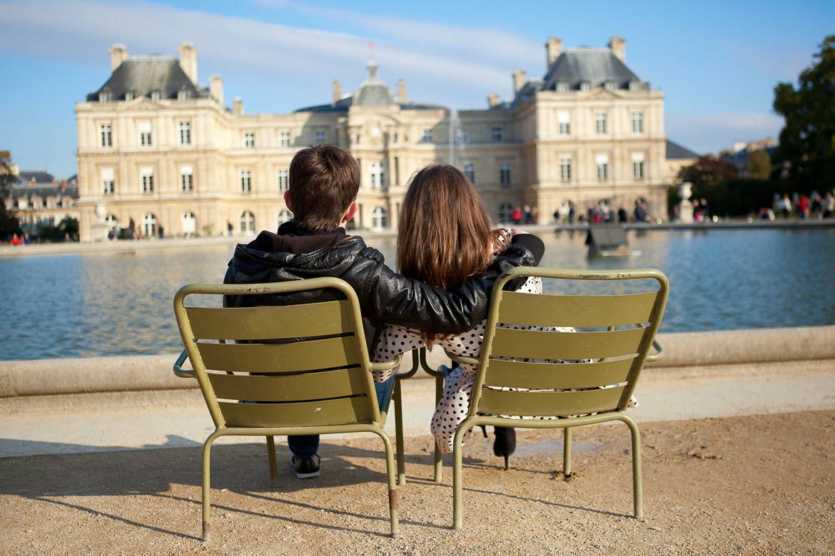 Image of a couple cuddling in front of the Palais du Luxembourg in Paris. 