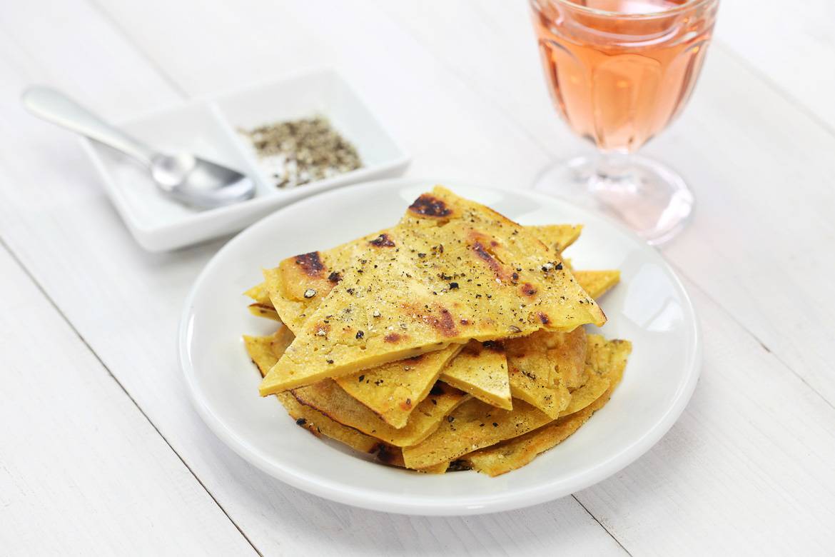Image of a place of slices of socca, salt and pepper, and a glass of rosé wine