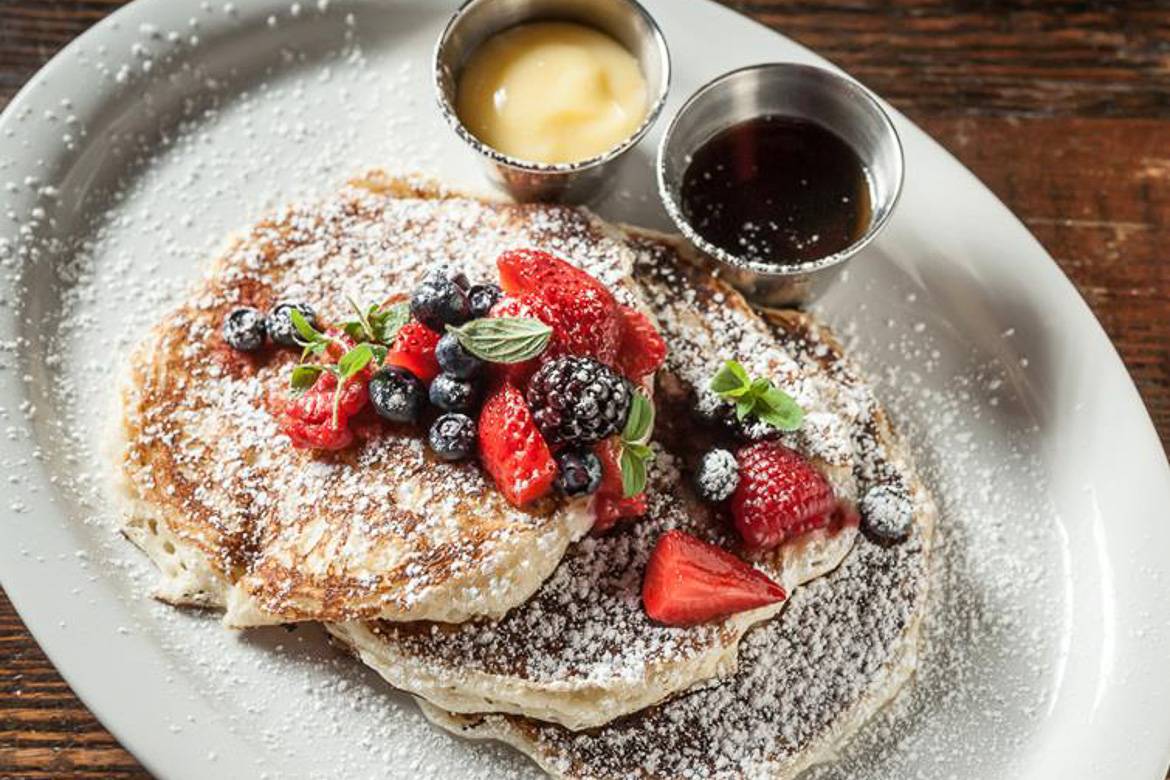 Image of pancakes topped with fruit and powdered sugar