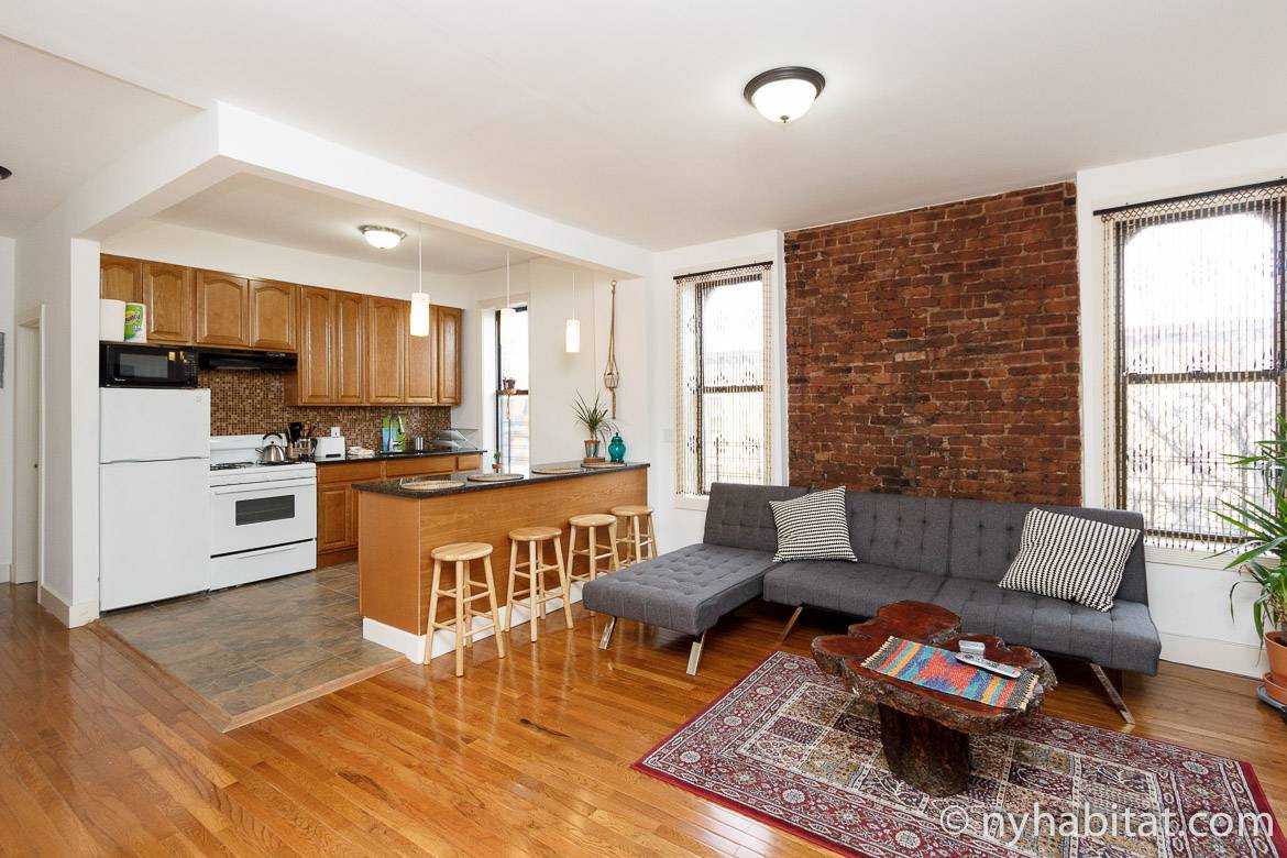 Image of an apartment living area with a kitchen and exposed brick
