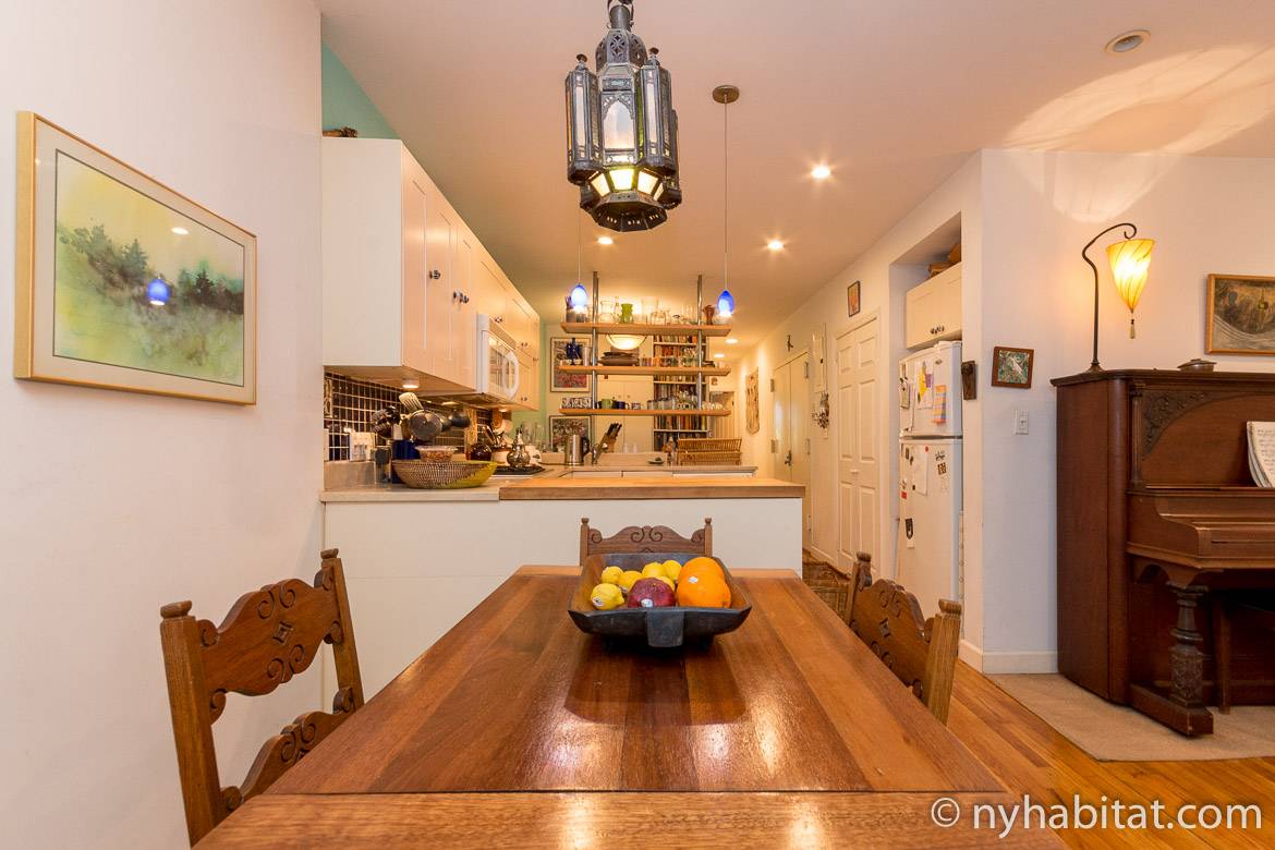 Image of an apartment with a wooden dining table and white kitchen