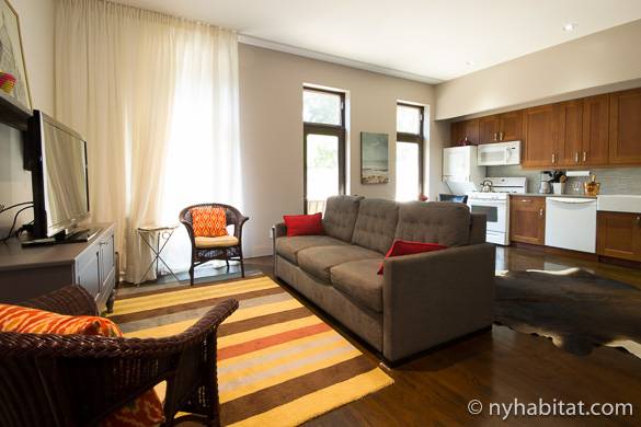Image of living room couch and TV of NY-15441 with kitchen in the background