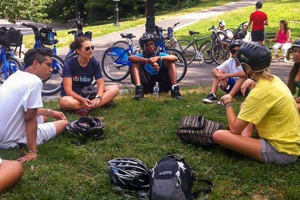 Image of people sitting in a circle in the park with bikes