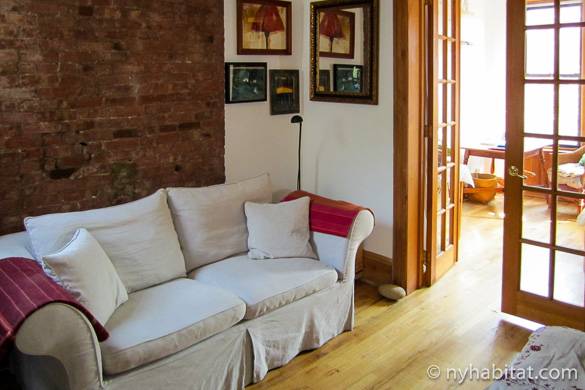 Image of living room of NY-3201 with sofa, French doors and brick walls
