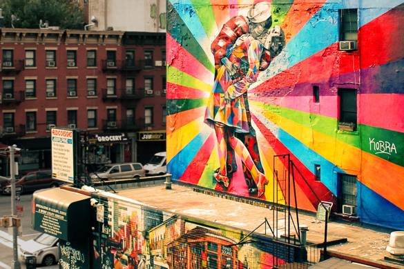 Image of street art graffiti on side of a building with iconic scene of sailor kissing woman in Times Square