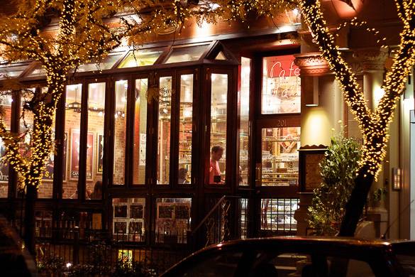 Image of the outside of Cafe Lalo with trees covered in string lights