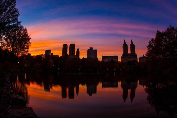 Image of silhouette of NYC skyline at sunset across the lake in Central Park