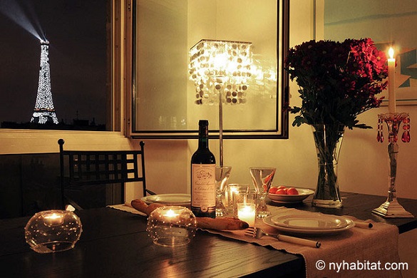 Image of dining table set with wine, flowers and candlelight with Eiffel Tower illuminated in the background