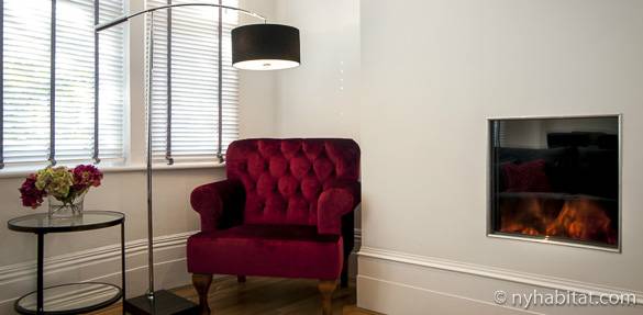 Image of a bright colored armchair next to a glass-covered fireplace