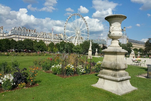 Image of park with plants and statues and Ferris wheel in the background