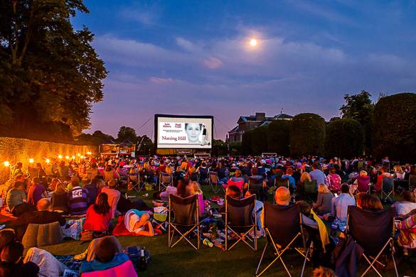 Image of people sitting outside watching a large movie screen