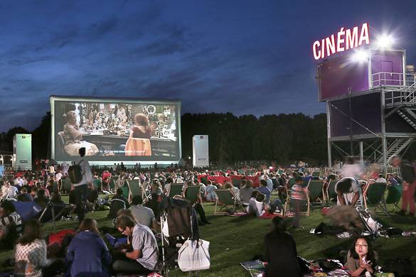 Image of people sitting on grass watching an outdoor movie