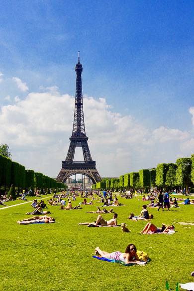 Image of people laying in the grass on the Champ-de-Mars with Eiffel Tower in background