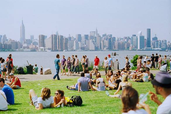 Image of people sitting on the grass at East River State Park with Manhattan skyline in the background