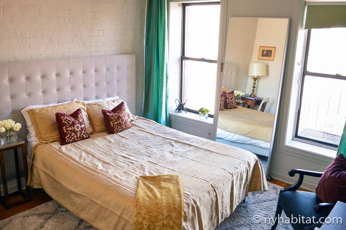 Image of wood-framed bed with throw pillows in bedroom of NY-11476 in the East Village
