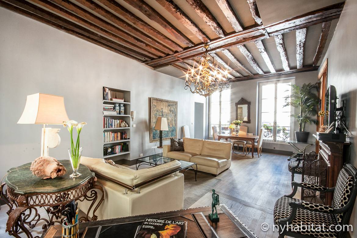 Image of living room of PA-1344 in the Marais with wood beam ceiling, chandelier, bookcases and sofas