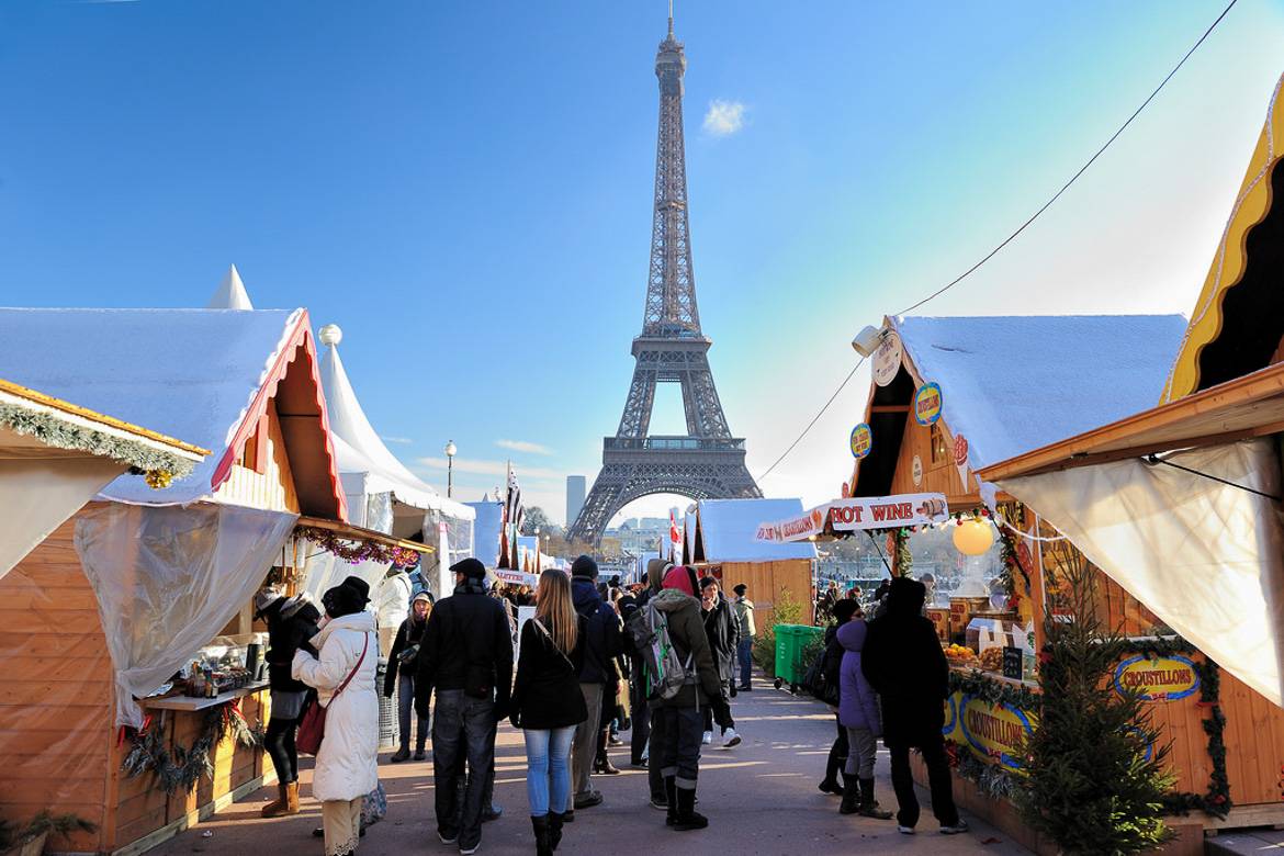 Image of Christmas market stalls in the shape of Alpine cottages with the Eiffel Tower in the background