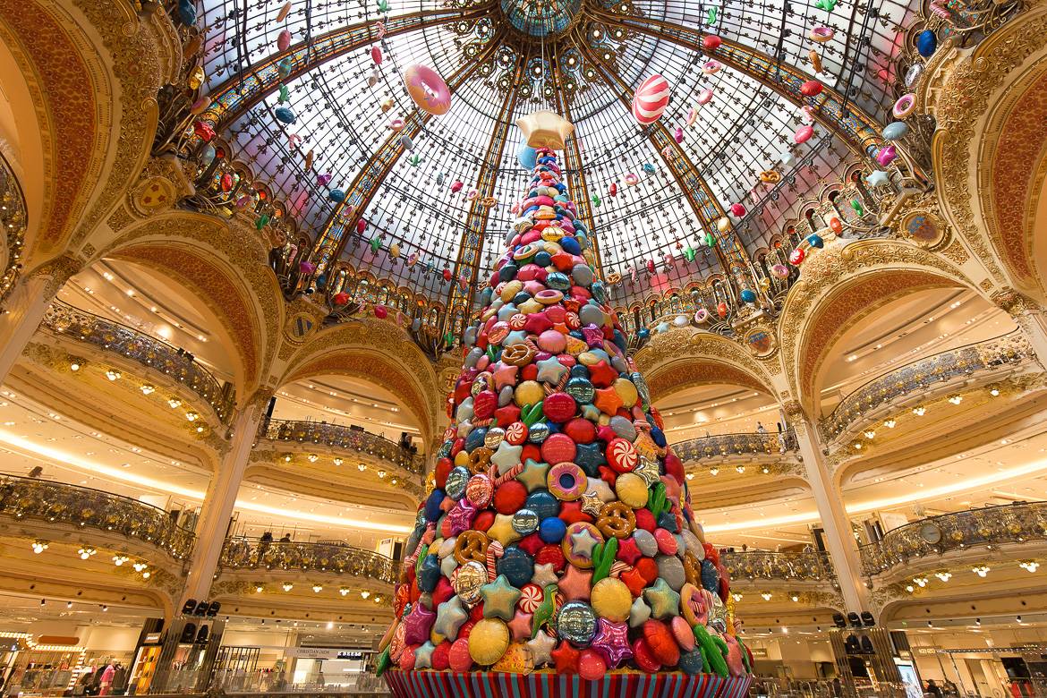 Image of the inside of Galeries Lafayette with arched balconies, Christmas tree, decorations and glass domed ceiling