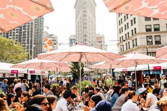 Image of people eating under sun umbrellas in the Flatiron District