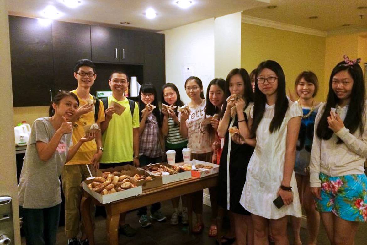 Image of a group of residents gathered in the common kitchen area of a residential building with donuts and coffee
