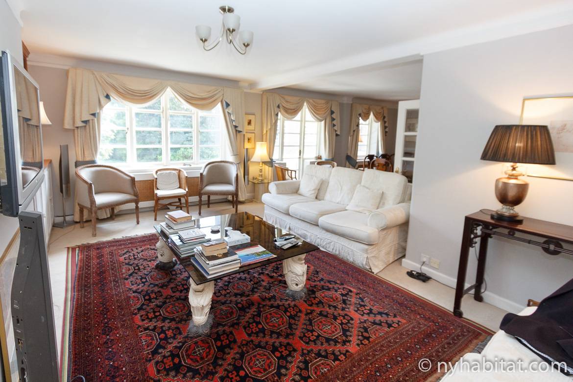 Image of living room of LN-1484 with red area rug, coffee table, sofa and 3 large windows