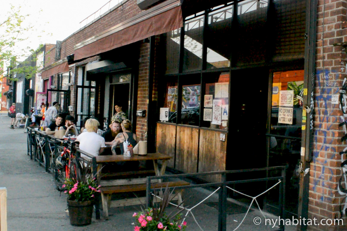 Image of people sitting at picnic tables outside the bar Anchored Inn