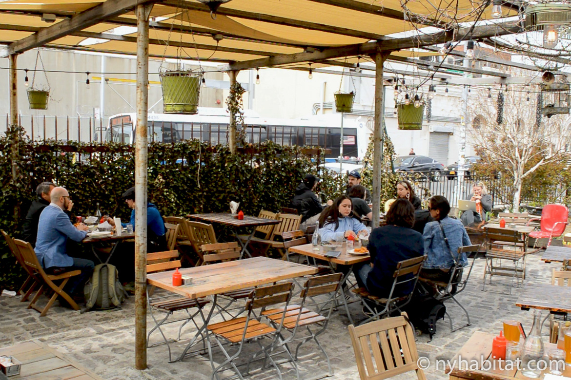 Image of people dining outside at wooden tables under a pergola at Forrest Point