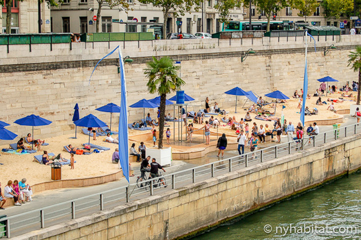 Image of people relaxing at Paris Plages along the Seine with blue umbrellas