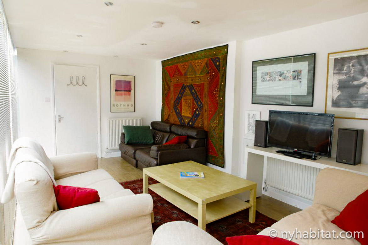 Image of living room in LN-1468 with white sofas, television and a red tapestry on the wall