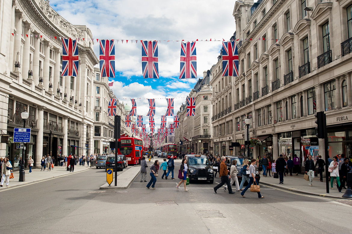 Image of people crossing a busy London street with the Union Jack flag overhead