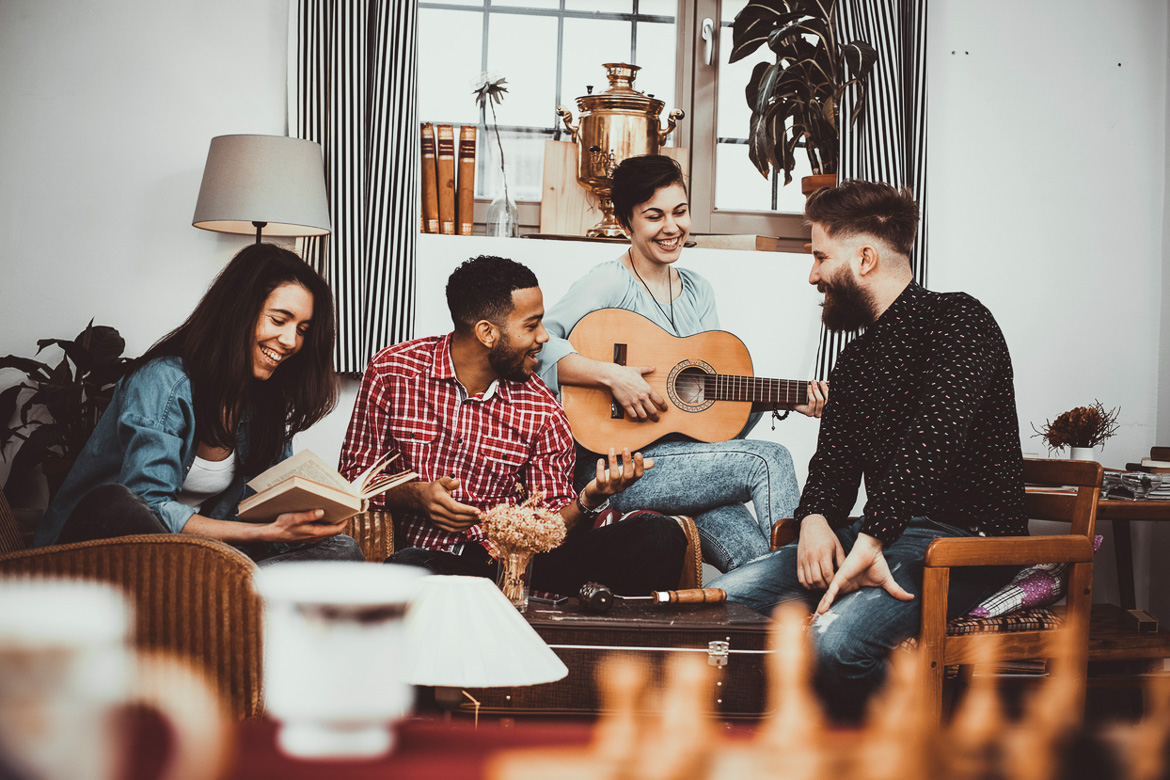Image of a group of young roommates playing music together in a shared apartment.