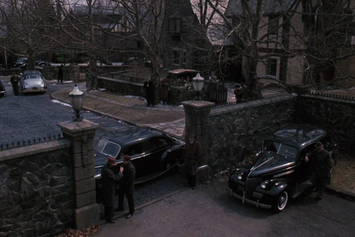 Image still of gates and cars outside the Corleone residence in the 1972 film The Godfather.
