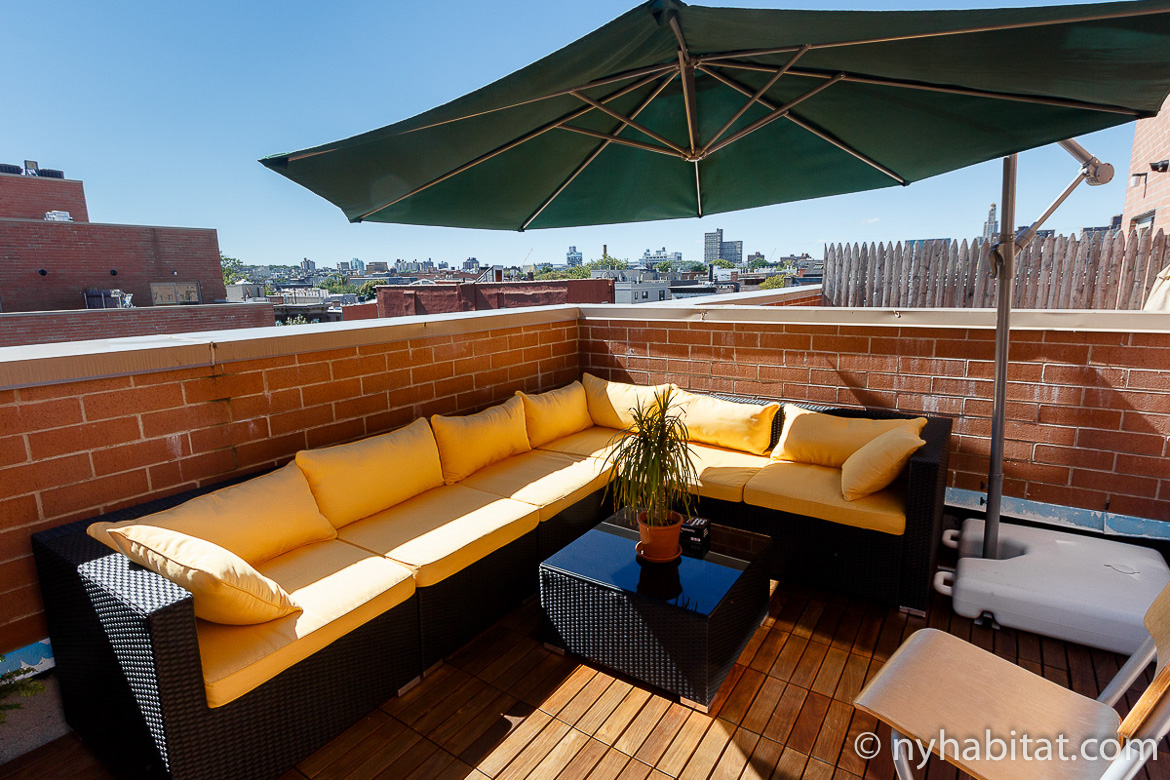 Image of terrace of NY-16001 with yellow sectional sofa and umbrella