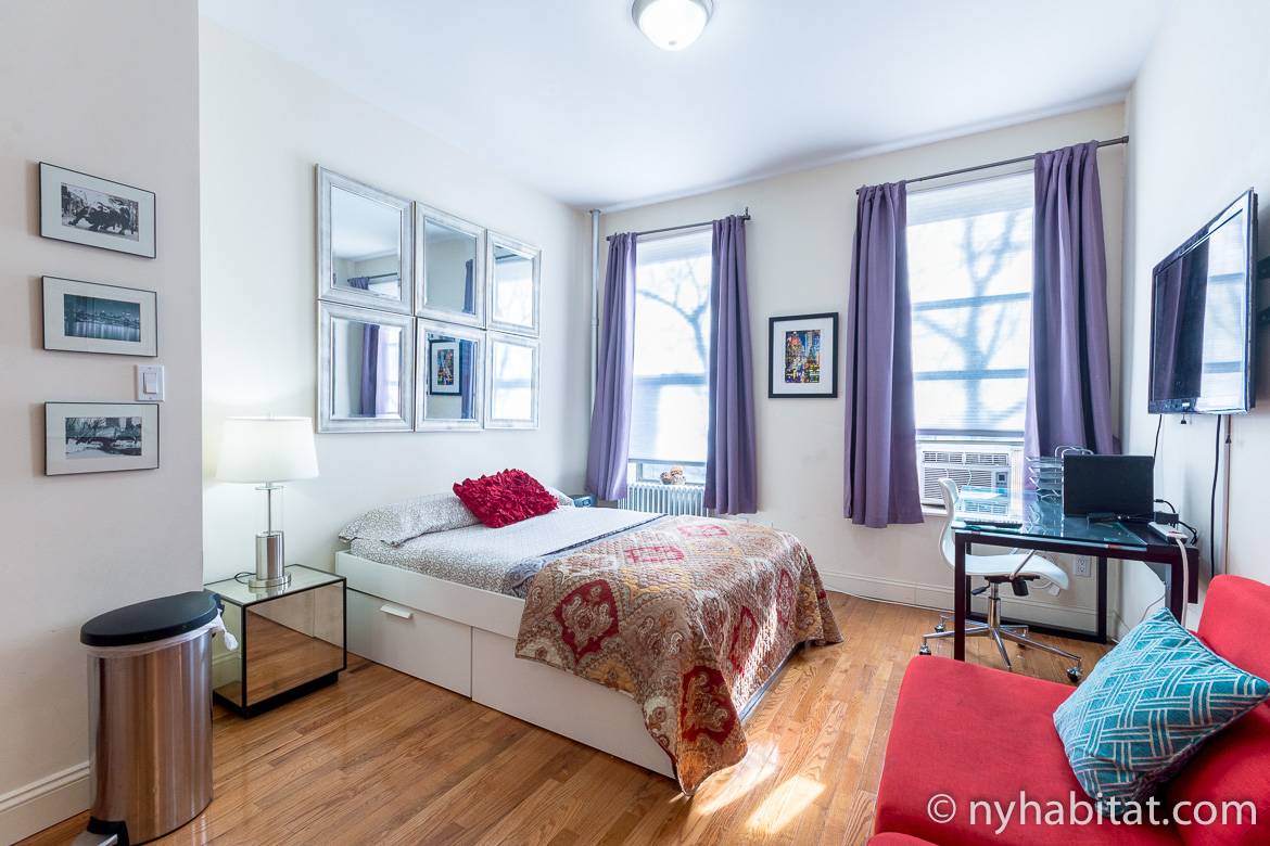 Image of living area in NY-17406 with double bed, two windows and artwork.