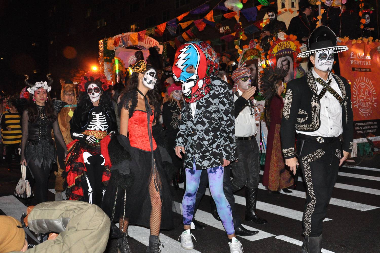 Image of people in face paint and Halloween costumes walking in the Village Halloween Parade.