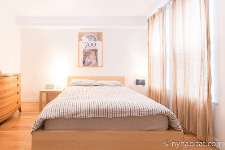 Image of bedroom in NY-14720 with queen-sized bed and curtained windows.