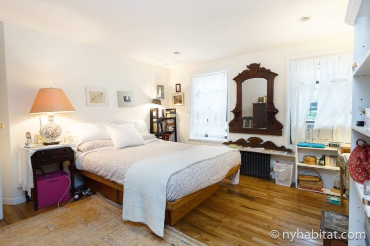 Image of bedroom in NY-16507 with queen-sized bed and bookshelves.
