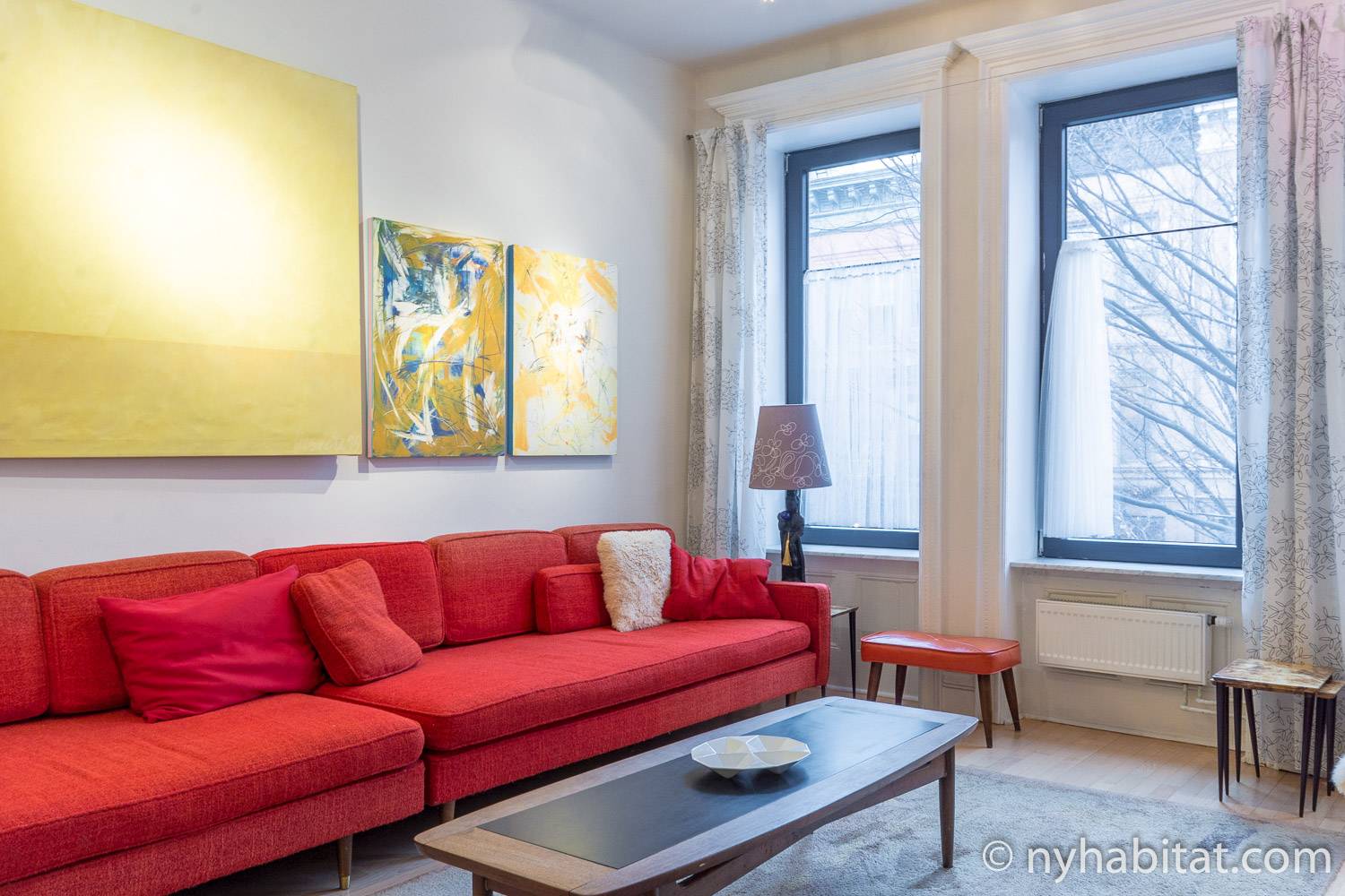 Image of living area in NY-12274 with large red sofa, artwork, and coffee table.