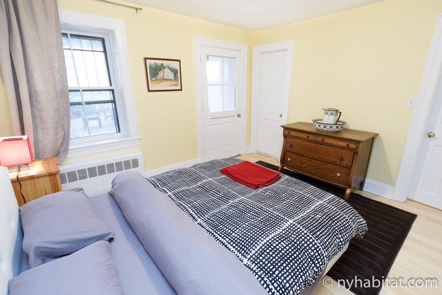 Image of bedroom in NY-16328 with queen-sized bed, side table and windows.
