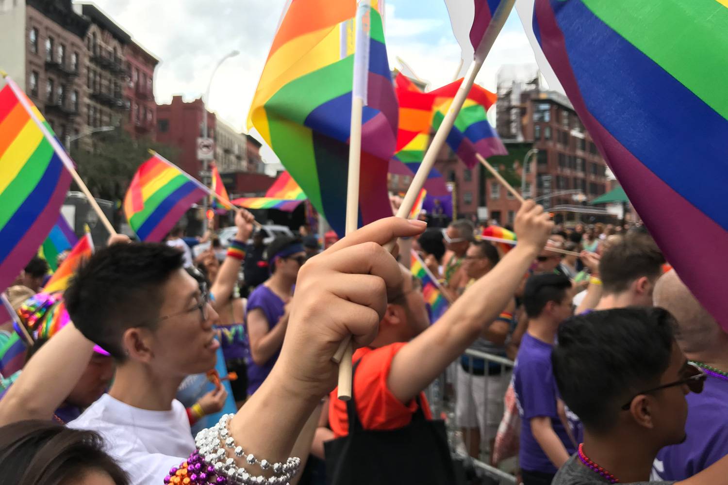 Image of participants in the 2018 LGBT Pride march in NYC waving rainbow flags.