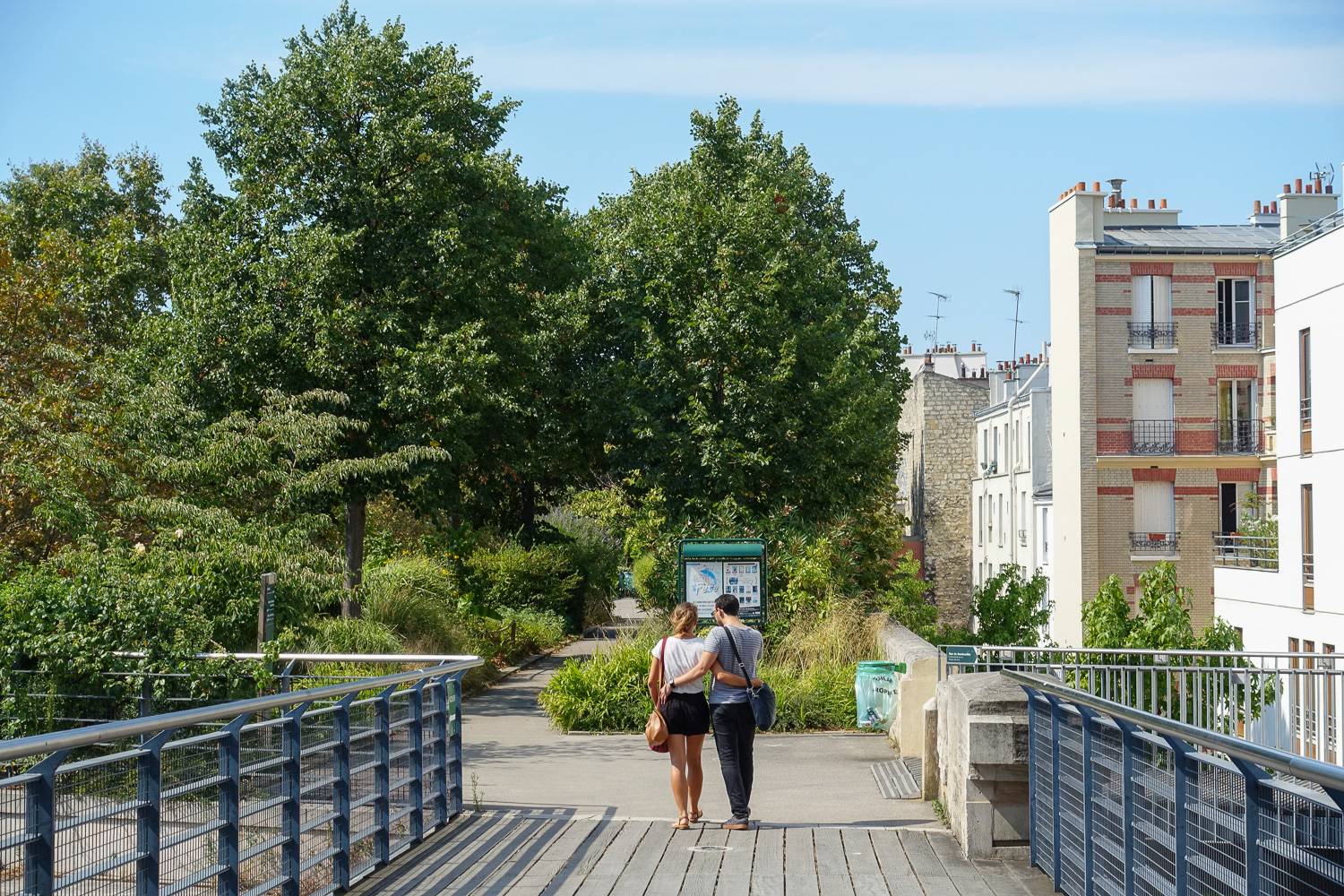 Image of a couple walking on the Coulée vert René-Dumont in summertime.
