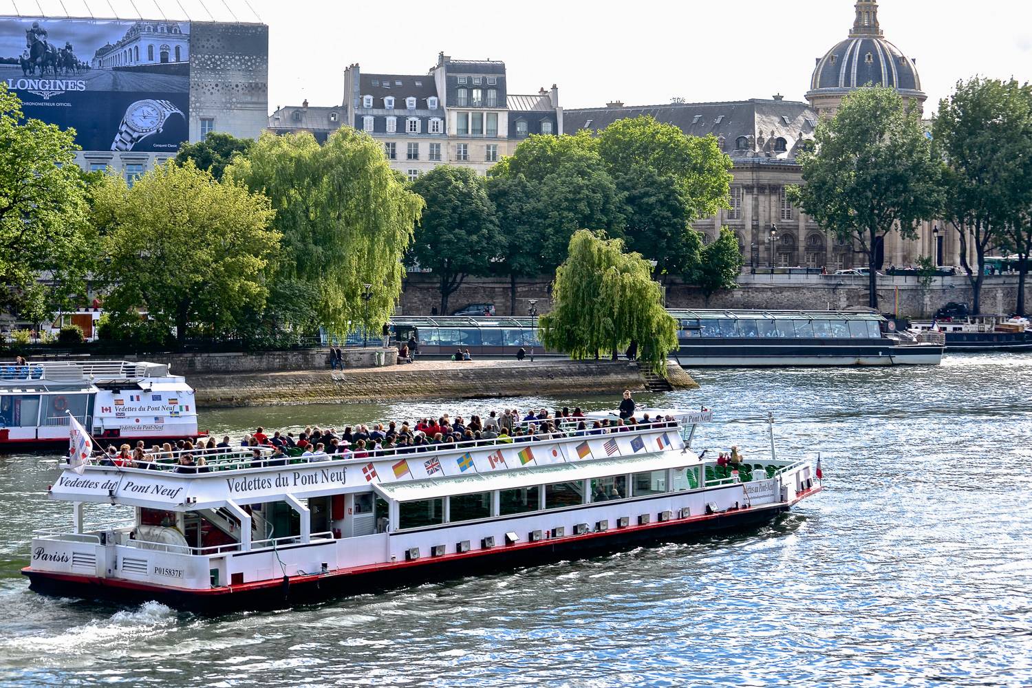 Image of a cruise boat filled with sightseers on the Seine in Paris.