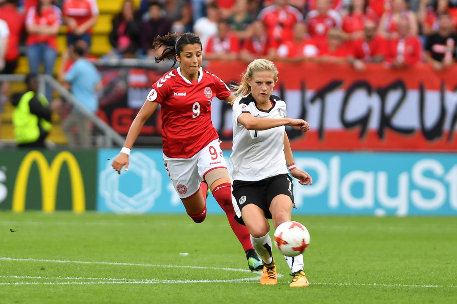Image of two women’s soccer players from Denmark and Austria playing a match.