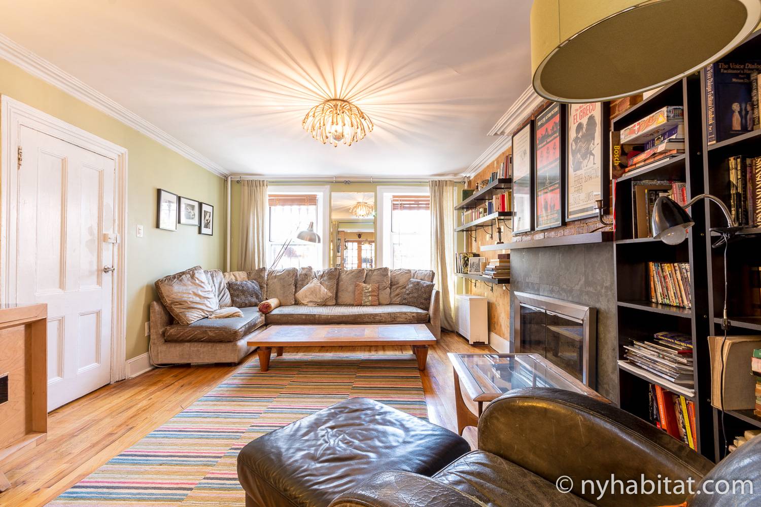 Image of living area of NY-12507 with decorative fireplace, sofa, chandelier, and armchair.