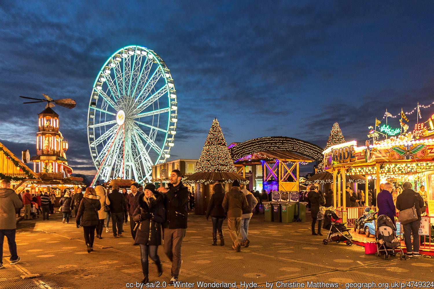 A photo of a bright Ferris wheel, Christmas trees, and a carousel at the annual London festival, Winter Wonderland.